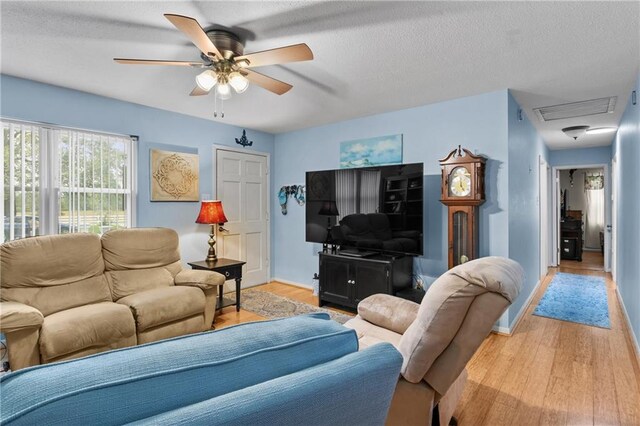 living room featuring light hardwood / wood-style flooring, a textured ceiling, and ceiling fan