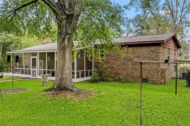 back of property featuring a yard, a sunroom, and central AC