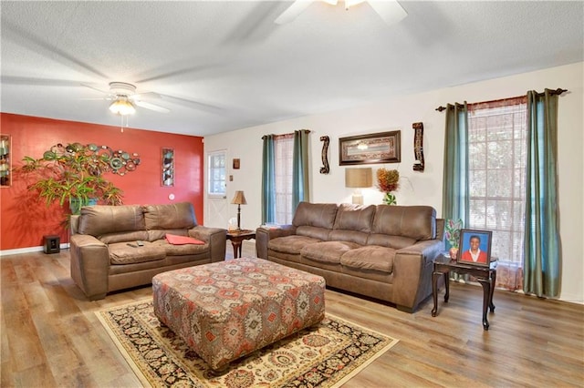 living room with a textured ceiling, light hardwood / wood-style floors, and ceiling fan