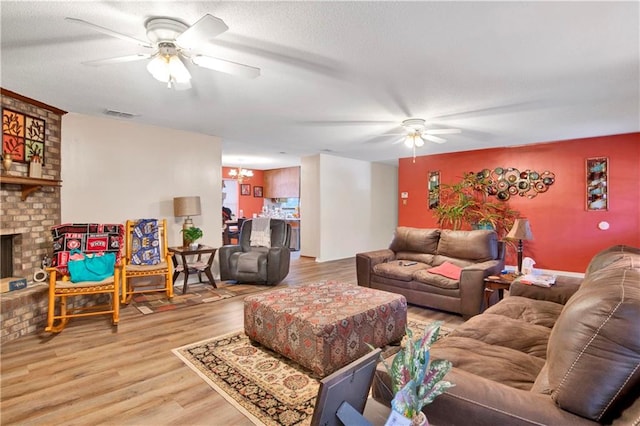 living room with a fireplace, wood-type flooring, and ceiling fan with notable chandelier