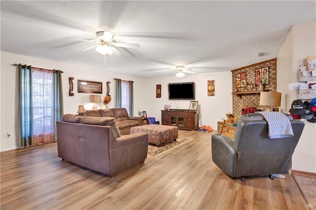 living room featuring a textured ceiling, light wood-type flooring, and ceiling fan