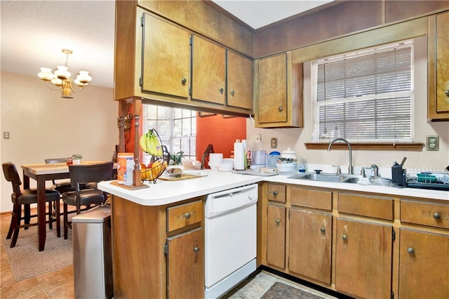 kitchen with kitchen peninsula, light tile patterned floors, an inviting chandelier, white dishwasher, and sink