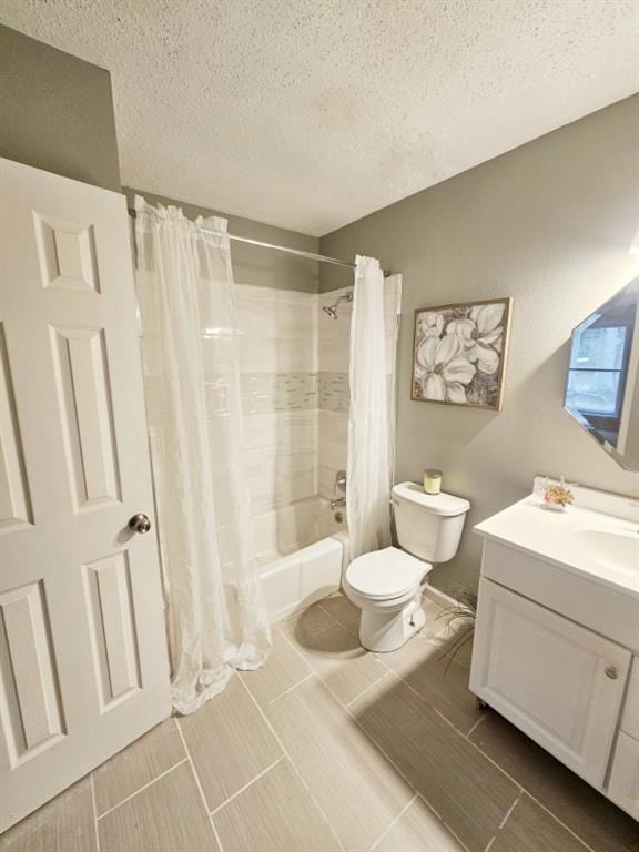 bathroom featuring shower / tub combo with curtain, vanity, toilet, and a textured ceiling