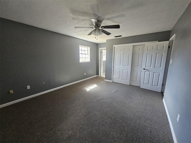 unfurnished bedroom with a textured ceiling, carpet flooring, visible vents, baseboards, and a closet