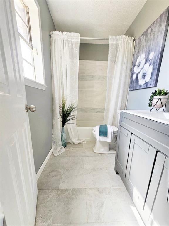 bathroom with a textured ceiling, toilet, vanity, baseboards, and shower / bath combination with curtain