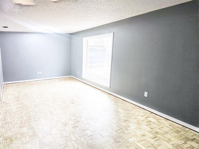 empty room featuring a textured ceiling and baseboards