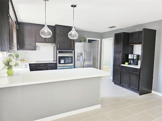 kitchen with under cabinet range hood, stainless steel appliances, a peninsula, a sink, and light countertops