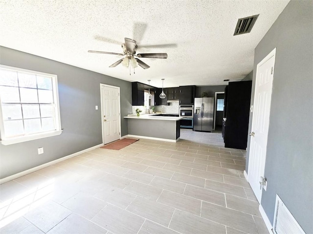 kitchen featuring stainless steel appliances, visible vents, light countertops, a ceiling fan, and a peninsula