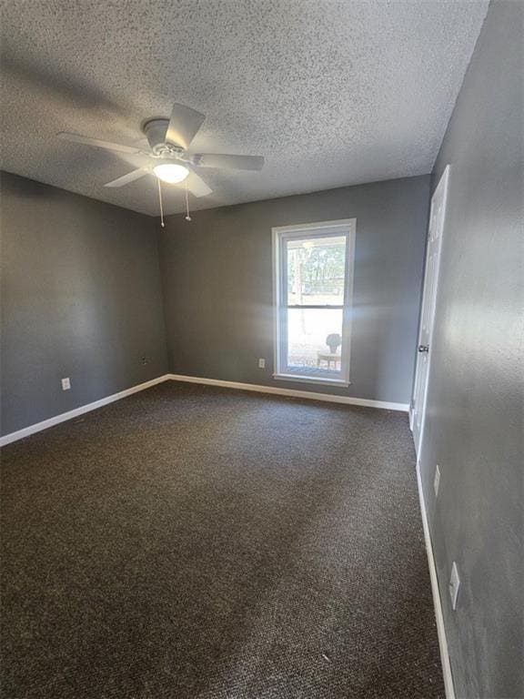 spare room with baseboards, dark carpet, ceiling fan, and a textured ceiling