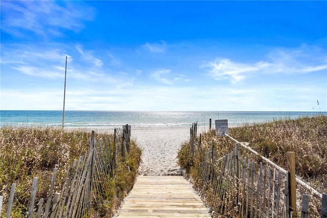 view of property's community featuring a water view and a beach view