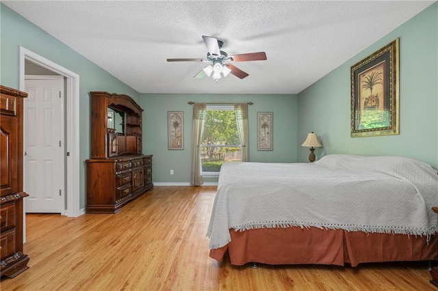 bedroom with ceiling fan, a textured ceiling, baseboards, and wood finished floors