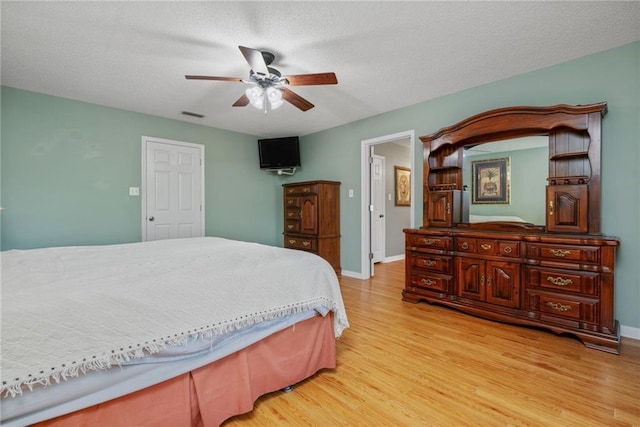 bedroom featuring ceiling fan, visible vents, baseboards, and light wood-type flooring