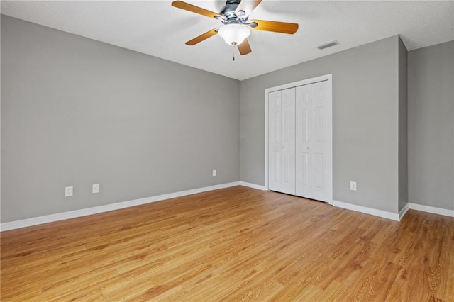 unfurnished bedroom featuring light wood-style flooring, a ceiling fan, baseboards, visible vents, and a closet