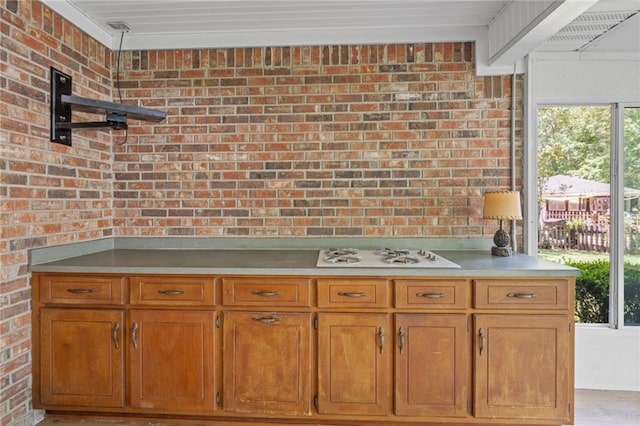 kitchen with brown cabinetry, brick wall, open shelves, light countertops, and white gas stovetop