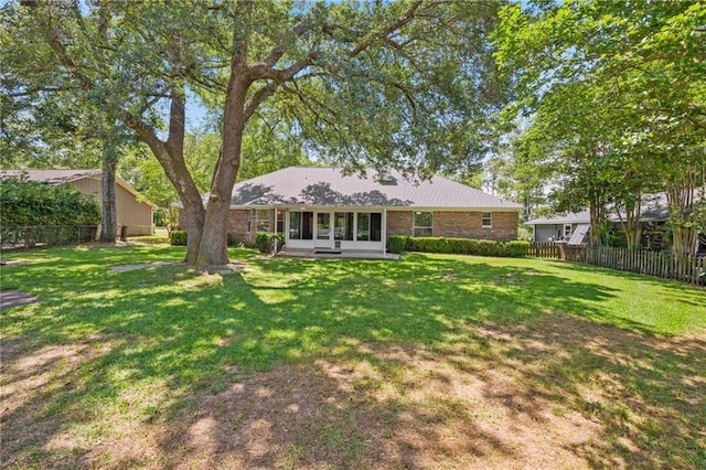 rear view of house featuring fence, a sunroom, and a yard