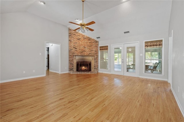 unfurnished living room featuring a fireplace, french doors, light wood-style flooring, a ceiling fan, and vaulted ceiling