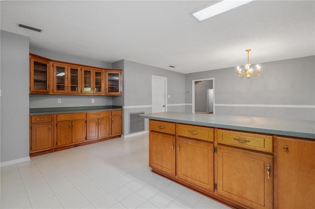 kitchen featuring brown cabinetry, glass insert cabinets, visible vents, and an inviting chandelier