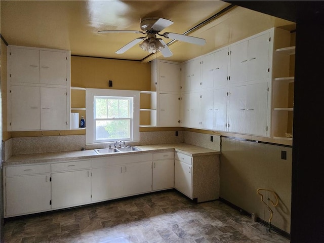 kitchen featuring ceiling fan, sink, and white cabinets