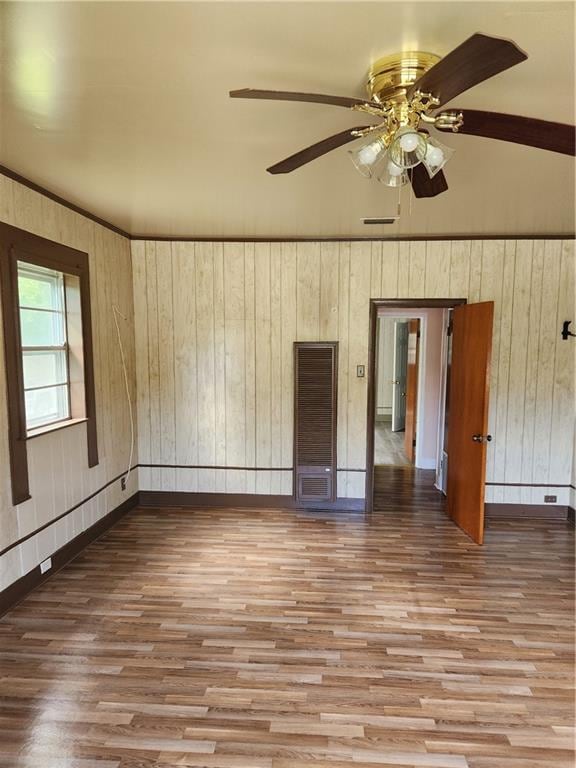 spare room featuring wood walls, ceiling fan, and hardwood / wood-style flooring