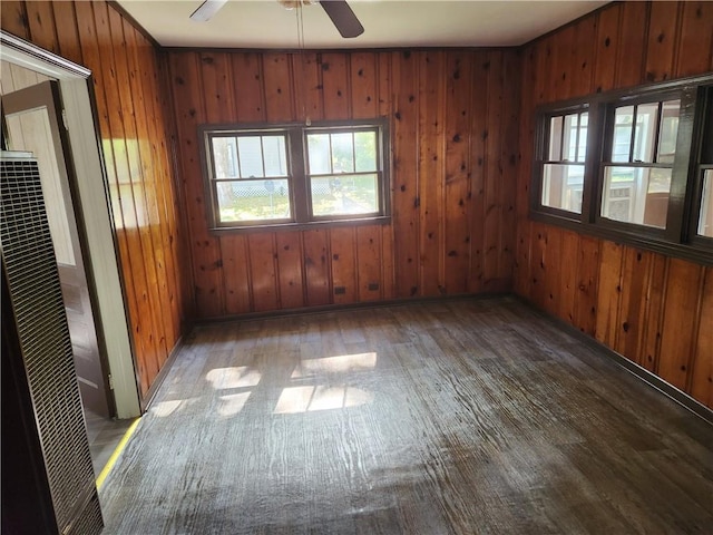 unfurnished room featuring hardwood / wood-style flooring, ceiling fan, and wooden walls