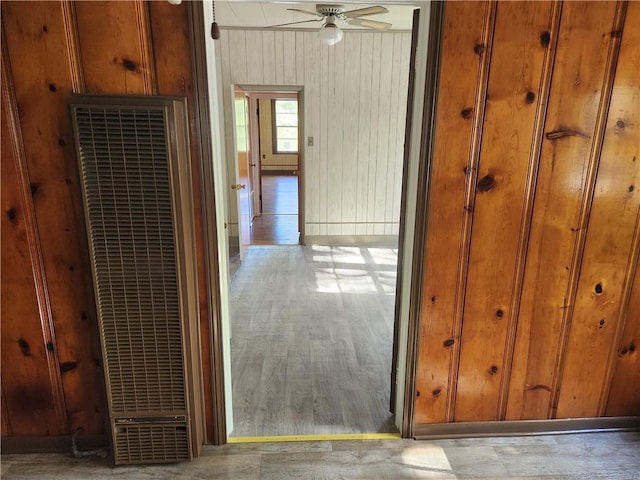 hallway featuring light wood-type flooring and wooden walls