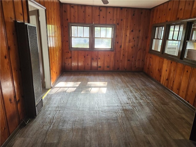 empty room featuring dark wood-type flooring, ceiling fan, and wood walls