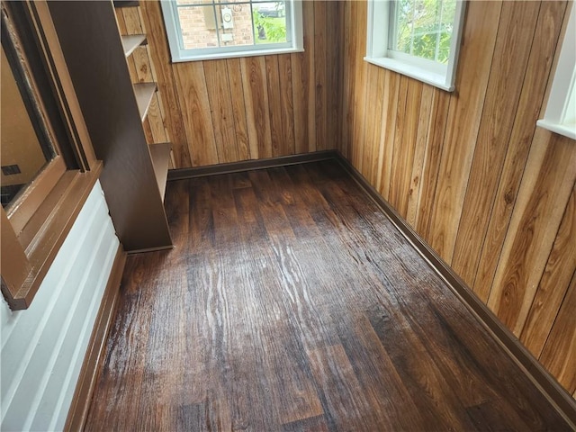 empty room with dark hardwood / wood-style flooring and wooden walls