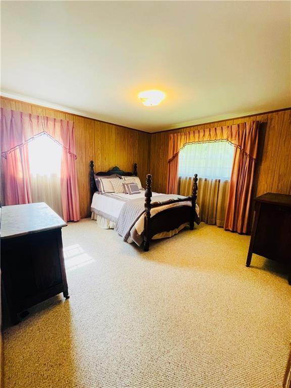 bedroom featuring light colored carpet and wood walls