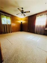 unfurnished room with ceiling fan and wood walls