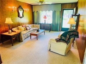 living room with wood walls, ceiling fan, and carpet