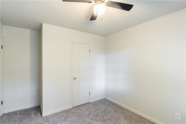 spare room featuring a textured ceiling, ceiling fan, and light carpet