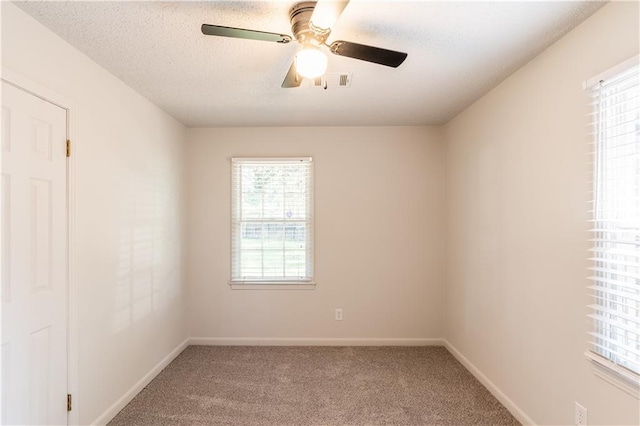 carpeted spare room with ceiling fan, a textured ceiling, and a wealth of natural light