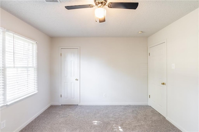 spare room featuring light carpet, a textured ceiling, and ceiling fan