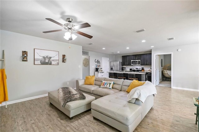 living area featuring light wood-style flooring, visible vents, and baseboards