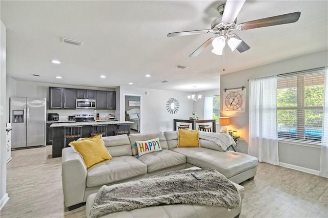 living area featuring recessed lighting, ceiling fan with notable chandelier, visible vents, baseboards, and light wood-style floors