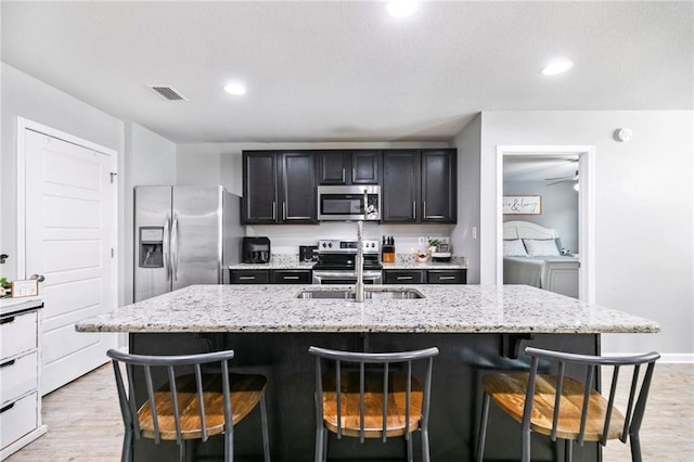 kitchen featuring light wood-type flooring, visible vents, stainless steel appliances, and a breakfast bar area