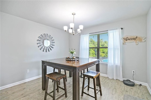 dining room featuring light wood-style floors, baseboards, and a chandelier