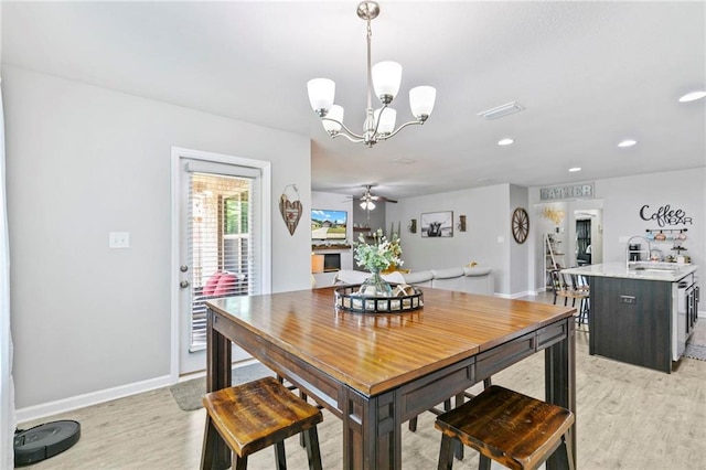 dining area featuring ceiling fan with notable chandelier, recessed lighting, baseboards, and light wood-style floors