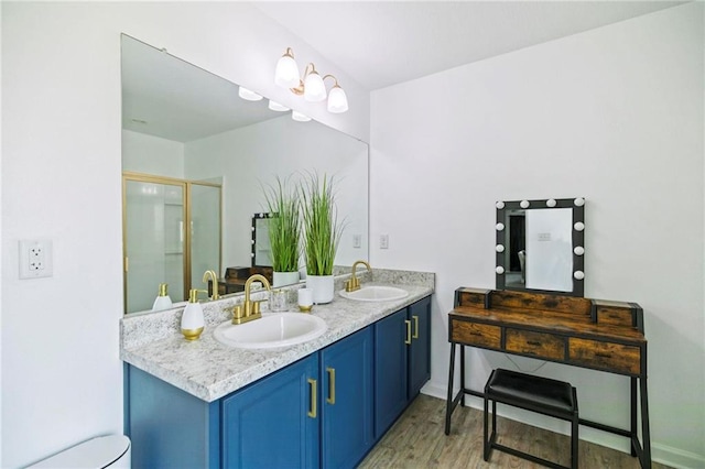 bathroom with double vanity, wood finished floors, a stall shower, and a sink