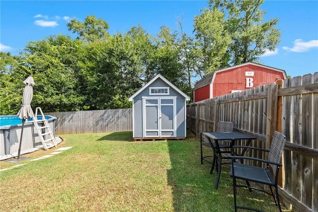 view of yard with a storage unit, an outdoor structure, a fenced backyard, and a fenced in pool