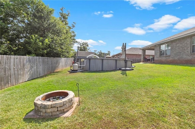 view of yard with an outdoor fire pit, a fenced backyard, and a swimming pool