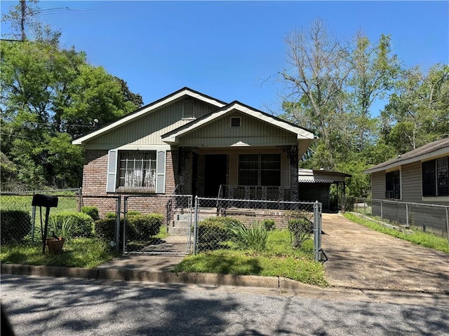 bungalow-style home featuring covered porch, a fenced front yard, brick siding, and a gate
