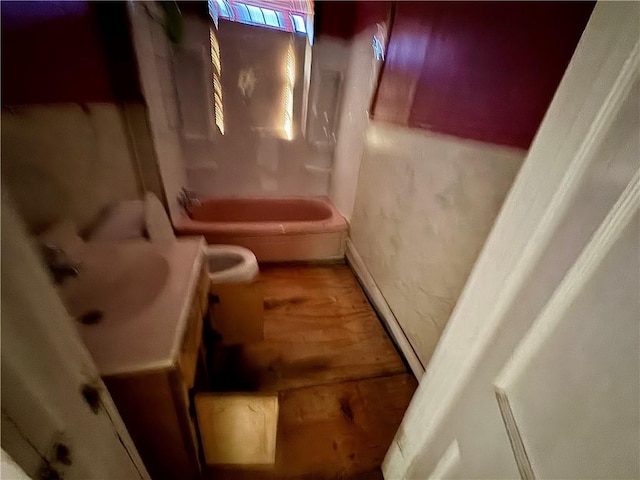bathroom featuring a tub, toilet, baseboards, and vanity
