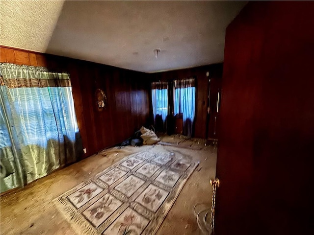 unfurnished bedroom with wooden walls, a textured ceiling, and carpet floors