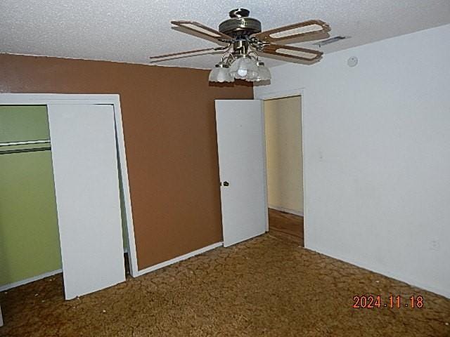 unfurnished bedroom with ceiling fan, carpet floors, a textured ceiling, and a closet