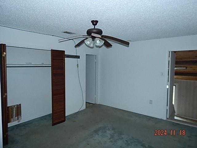 unfurnished bedroom with ceiling fan, dark carpet, and a textured ceiling