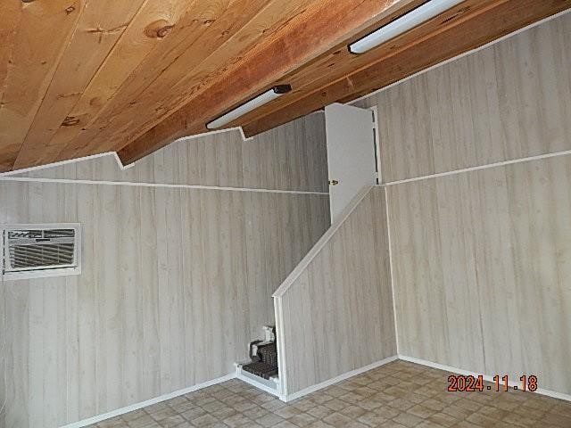 additional living space with a wall mounted air conditioner, wooden ceiling, lofted ceiling, and wood walls