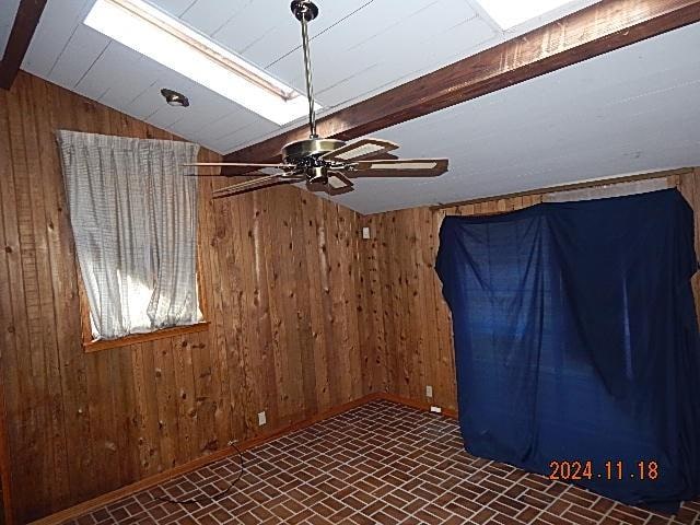 interior space with vaulted ceiling, ceiling fan, and wooden walls