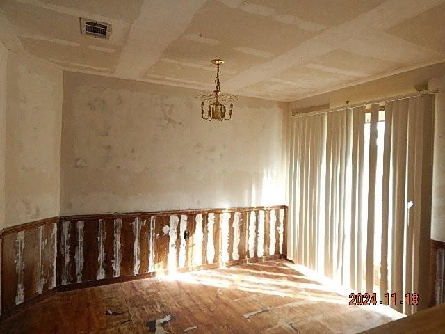 unfurnished room with wood-type flooring, a notable chandelier, and coffered ceiling