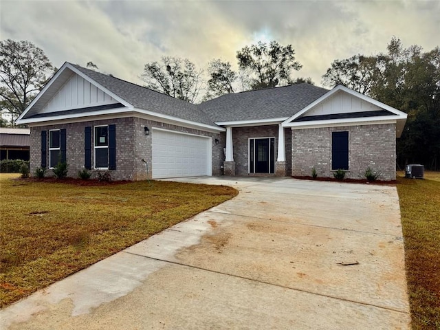 view of front of property with brick siding, an attached garage, a front yard, central AC, and driveway